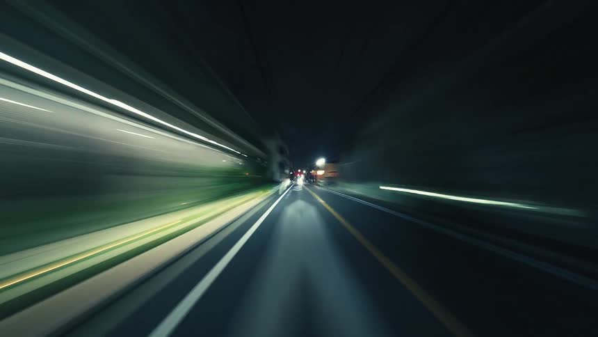 A dynamic POV hyperlapse of driving through a city at night, with streetlights and traffic creating vibrant, blurred light trails