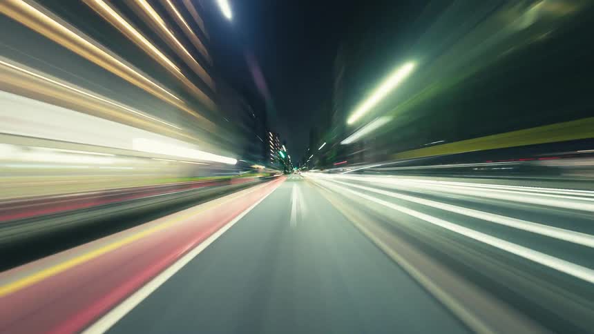 A thrilling time-lapse from the driver's perspective speeding through a vibrant city at night, with lights blurring into long colorful streaks