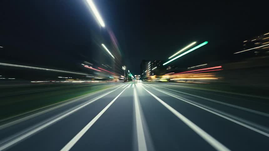 A dynamic point-of-view hyperlapse captures the vibrant energy of a nighttime drive through a city with colorful light trails