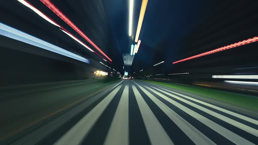 Dynamic hyper-lapse captures a speedy drive through a modern city at night, with vibrant light trails