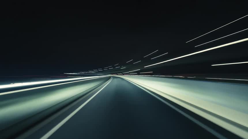 Abstract time-lapse driving through a dark city highway at night, showcasing brilliant light trails and high-speed motion