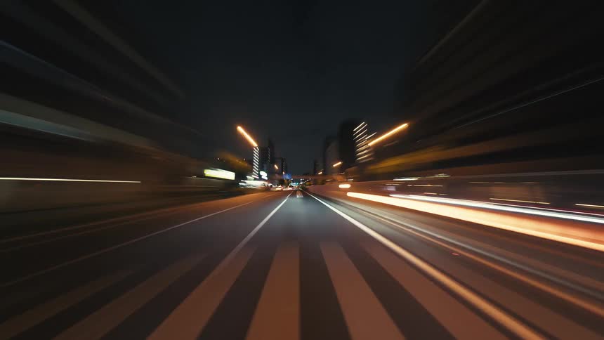 An electrifying POV hyperlapse captures the blur of city lights while speeding through urban streets at night