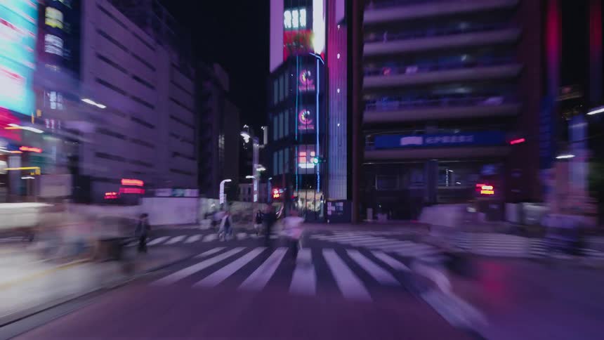 A fast-paced, motion-blurred hyperlapse drives down a city street illuminated by colorful neon lights at night
