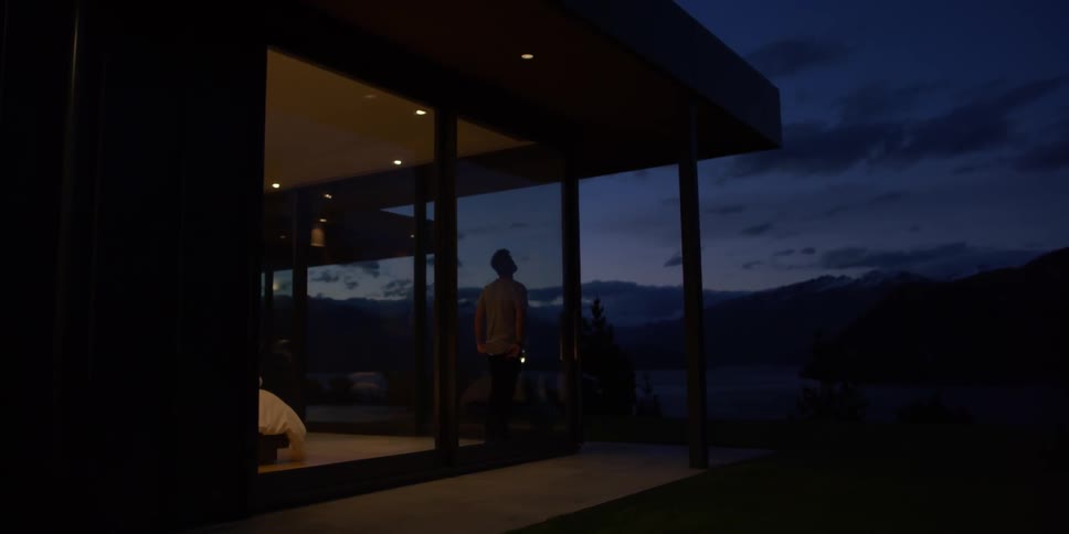 A man looks out the window at dawn