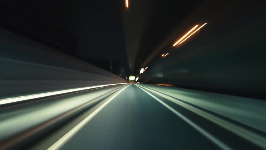 A fast-paced POV time-lapse captures the vibrant energy of driving through a city highway at night, with streaks of light from cars and streetlights blurring by