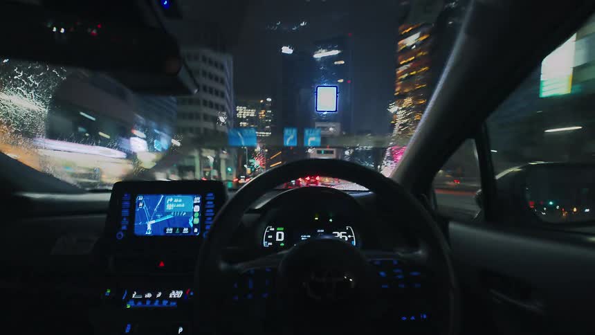 A first-person point-of-view time-lapse of driving through a vibrant city with neon lights on a rainy night