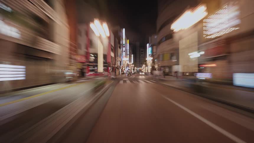 A dizzying first-person view hyperlapse speeds through the illuminated streets of a modern Asian city at night