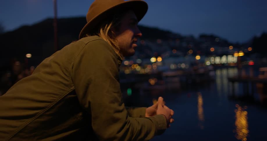 A man leans over a rail while looking at a lake