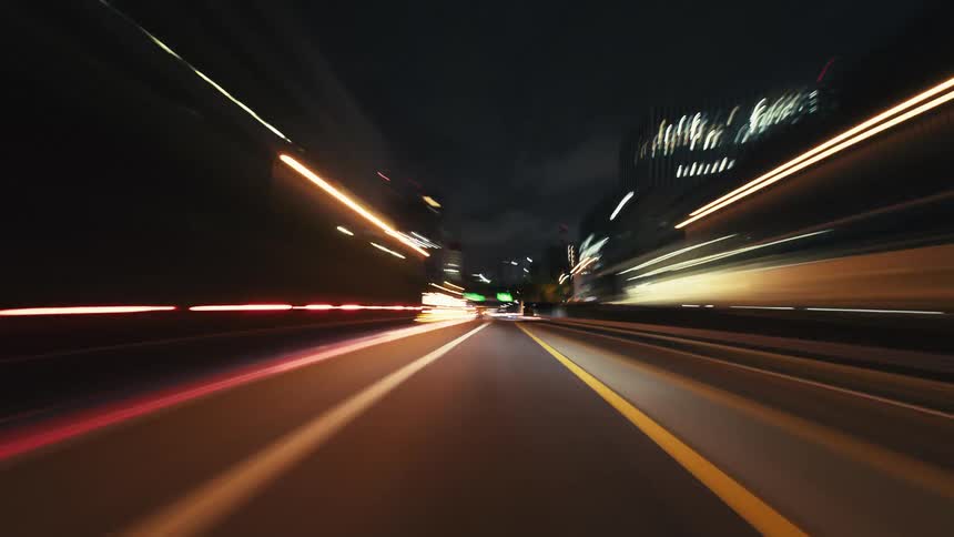 An exhilarating first-person hyperlapse captures a high-speed drive through a city's glowing highways and tunnels at night