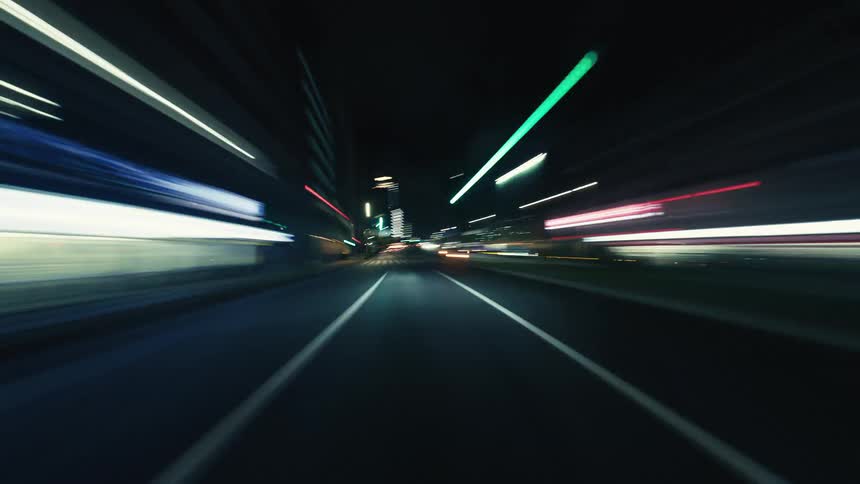 Point-of-view hyperlapse captures the energetic blur of city lights while driving at high speed through urban streets at night