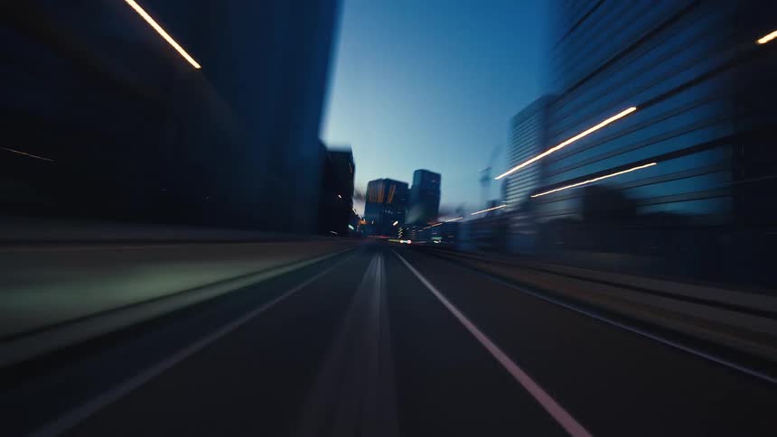 A dynamic point-of-view hyperlapse of driving through a modern city's highway at twilight, with motion-blurred buildings and light trails
