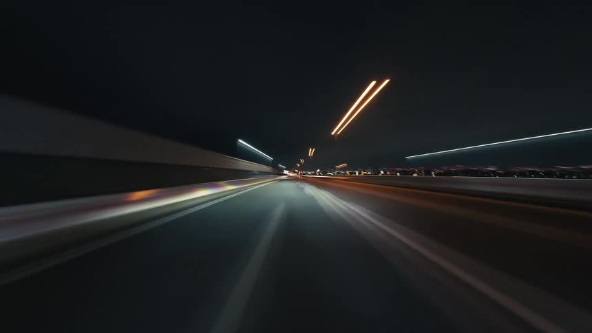 A futuristic time-lapse from the driver's perspective speeds through a city tunnel and onto the highway at night, creating vibrant light trails