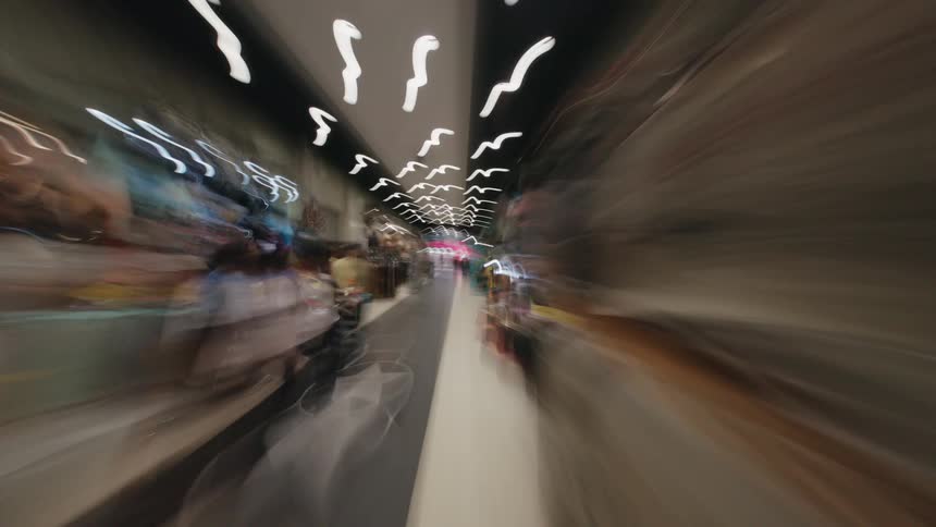 A dizzying first-person point-of-view hyperlapse rushes through a narrow indoor market, creating abstract streaks of light