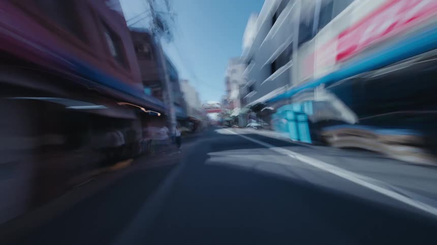 A surreal first-person hyperlapse speeds through the blurred streets of a Japanese city on a sunny day