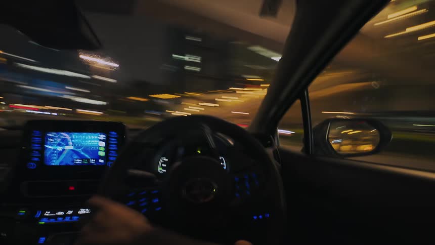 A fast-paced point-of-view hyper-lapse of driving through the brightly lit streets and tunnels of a modern city at night