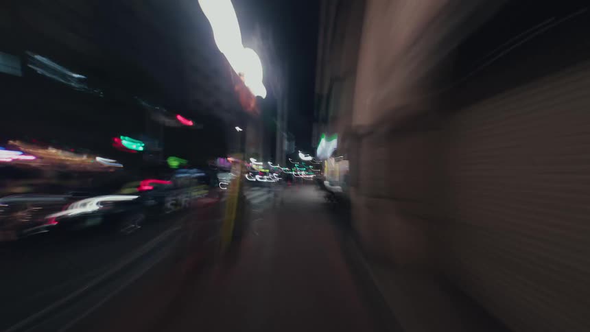 An abstract first-person hyperlapse captures a dizzying, fast-paced journey through a city at night as lights blur into colorful streaks