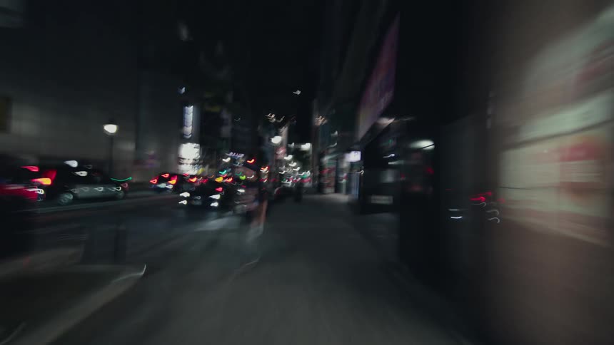 A dizzying first-person hyperlapse captures a fast-paced, blurry journey through the vibrant, neon-lit streets of a city at night