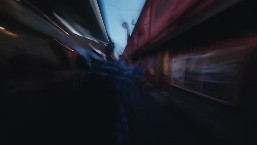 A dizzying first-person hyperlapse speeds through the bustling, narrow market streets of a vibrant Asian city with a motion blur effect