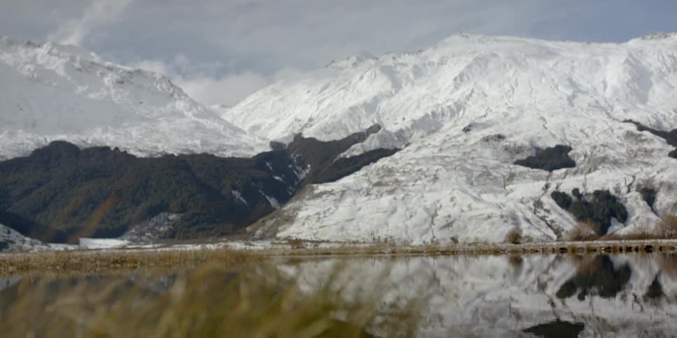 The snow covered mountains have a lake below