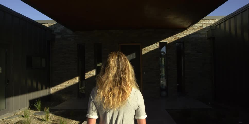A woman walks towards the porch of her home