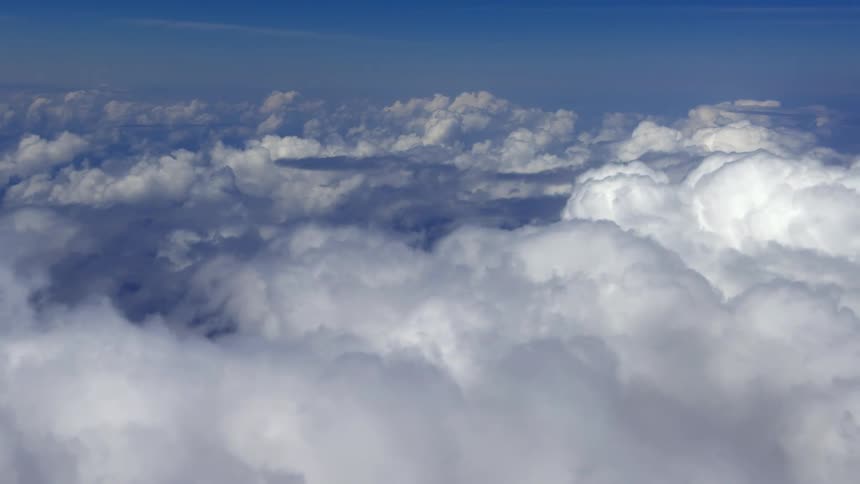 A serene and breathtaking aerial view of flying above a vast sea of white, fluffy clouds under a clear blue sky
