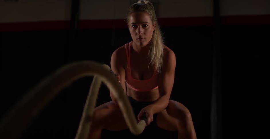 A woman exercises using two heavy ropes