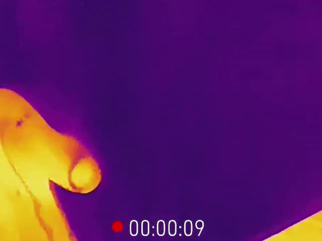 A close-up thermal imaging view captures cold liquid being poured over a warm human hand
