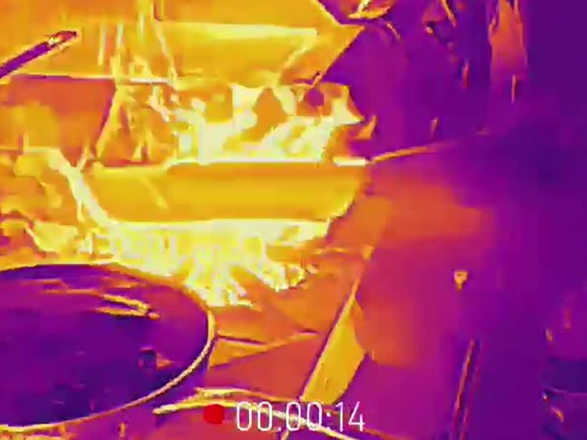 Close-up thermal footage shows a chef creating a fiery flambe in a wok on a hot stove