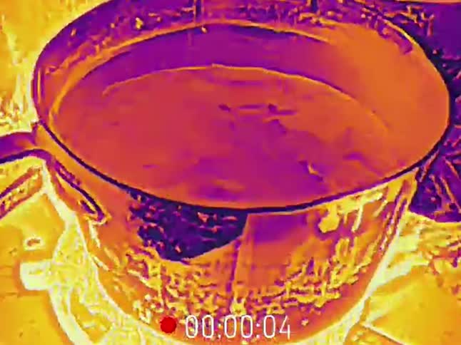 Close-up thermal imaging view of a pot of liquid heating up and simmering on a stove