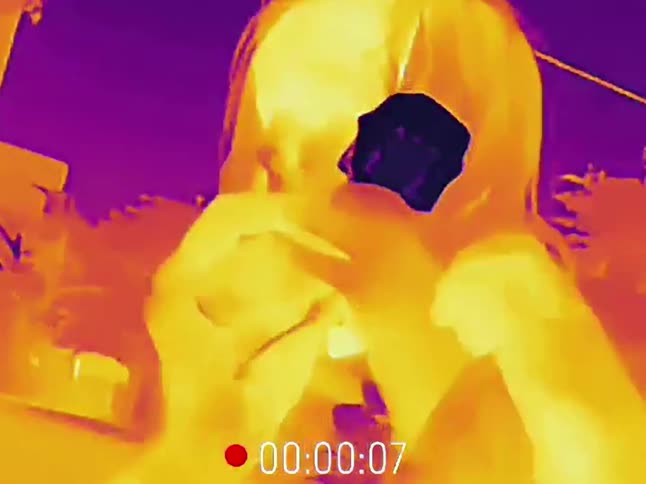Thermal vision captures a man and woman dancing energetically at an outdoor night event