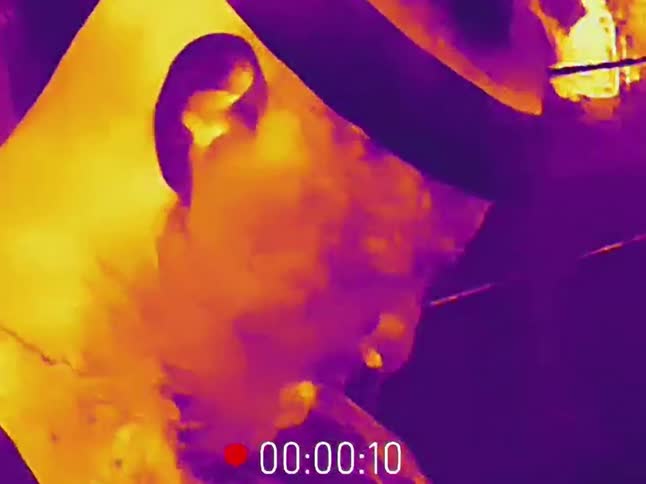 Infrared thermal imaging captures a close-up of a man yawning in a dark room
