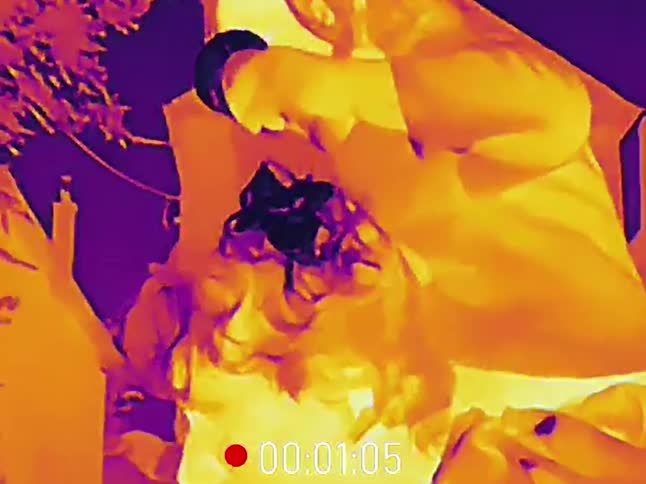 Santa Claus spies through binoculars at night, captured on a thermal imaging camera
