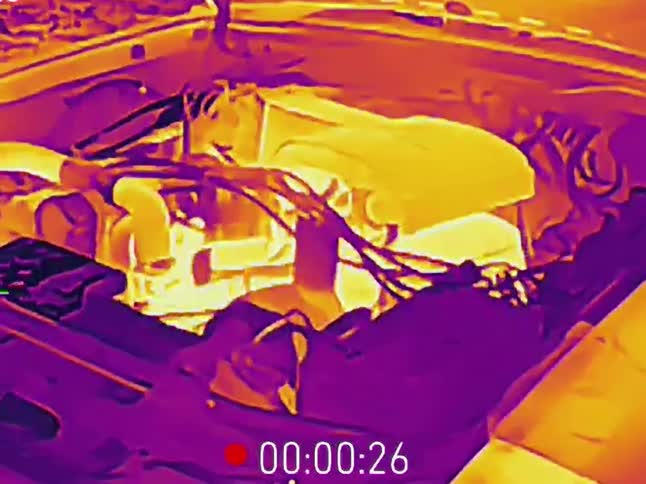Thermal imaging reveals the intense heat radiating from a car's engine after the hood is opened