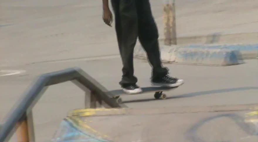 A skateboarder executes a kickflip off a ledge at an urban skatepark