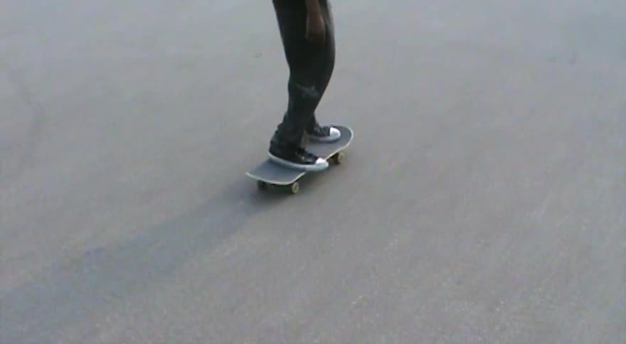 A skateboarder attempts a kickflip in slow motion but fails to land the trick