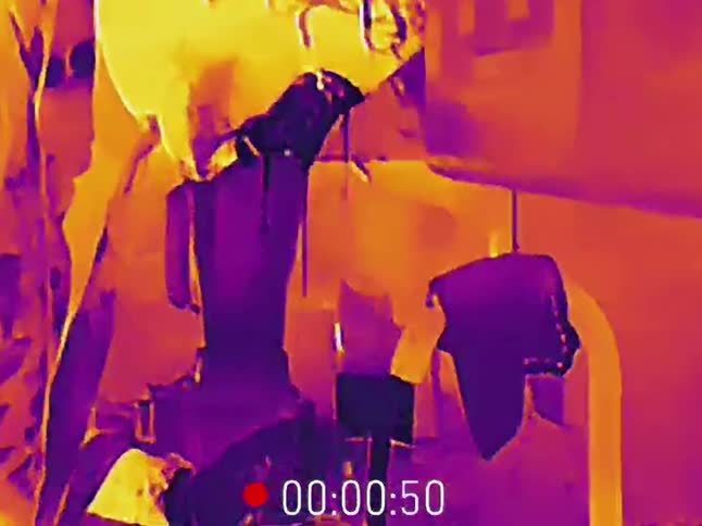 A close-up thermal camera view captures two people preparing a drink in a blender