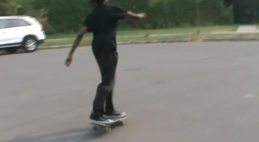 A skateboarder lands a kickflip in slow motion on a suburban street and then fails a second attempt