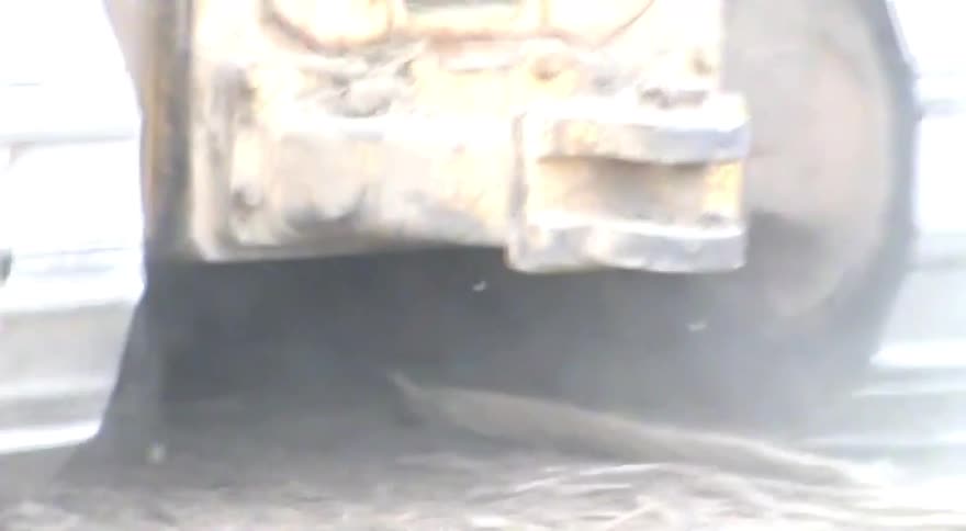 Close-up view of a bulldozer's metal caterpillar tracks turning on a dusty construction site