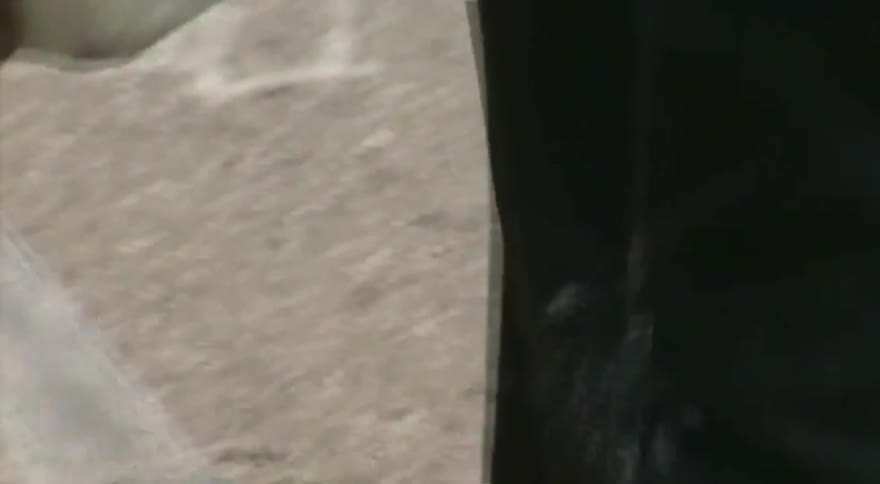 A close-up of a skateboarder applying a block of wax to a metal rail at a skatepark