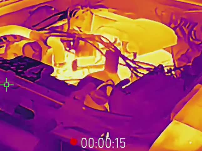 Thermal imaging camera view of a car hood being opened to reveal the hot engine bay for inspection