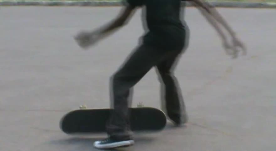 A close-up slow-motion shot of a skateboarder attempting and failing a kickflip on the street