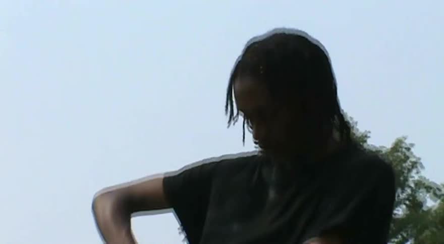A young skateboarder from a low angle applies wax to a wooden ledge at an outdoor skatepark