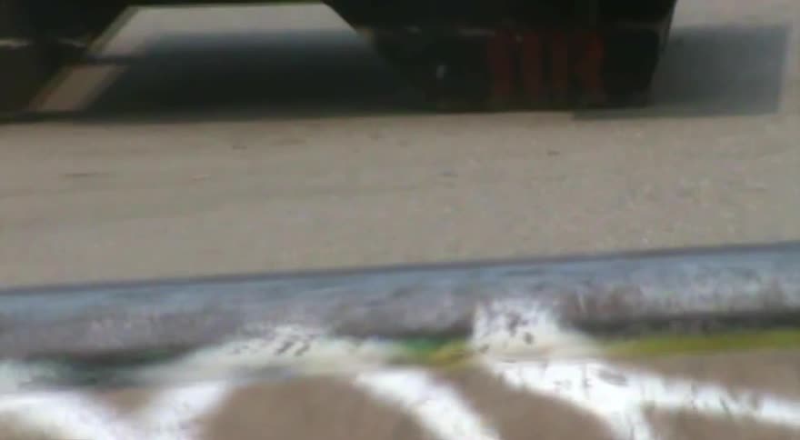 A close-up of a person's feet riding a skateboard at an urban skatepark