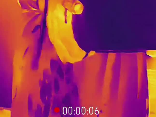 Thermal camera footage captures the heat transfer as a hand wipes a surface with a cool liquid