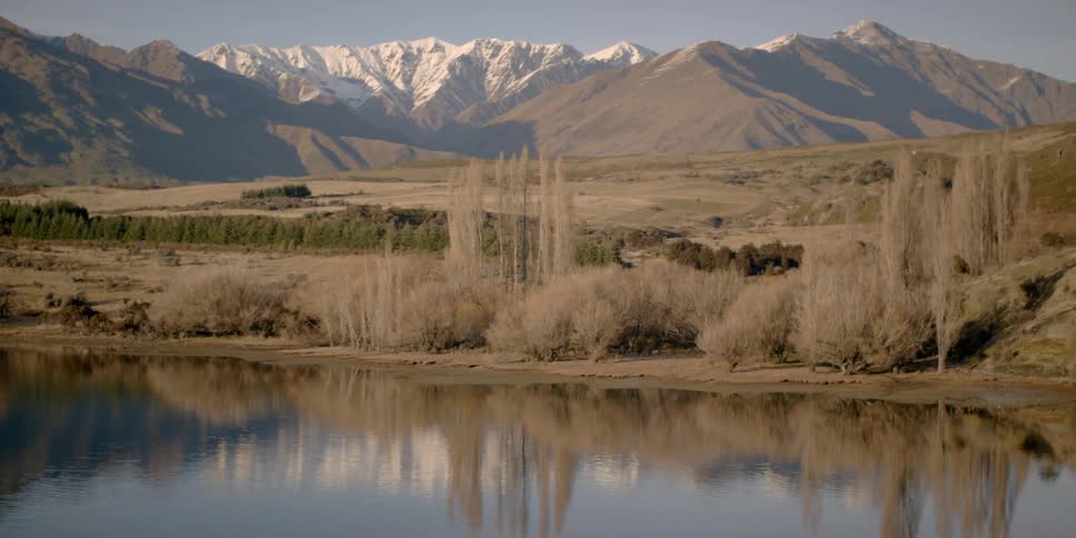 The lake is surrounded by grass and a mountain in the distance