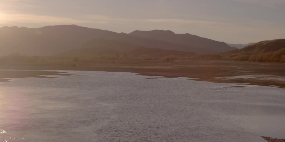 A mountain lake is shown at sunset