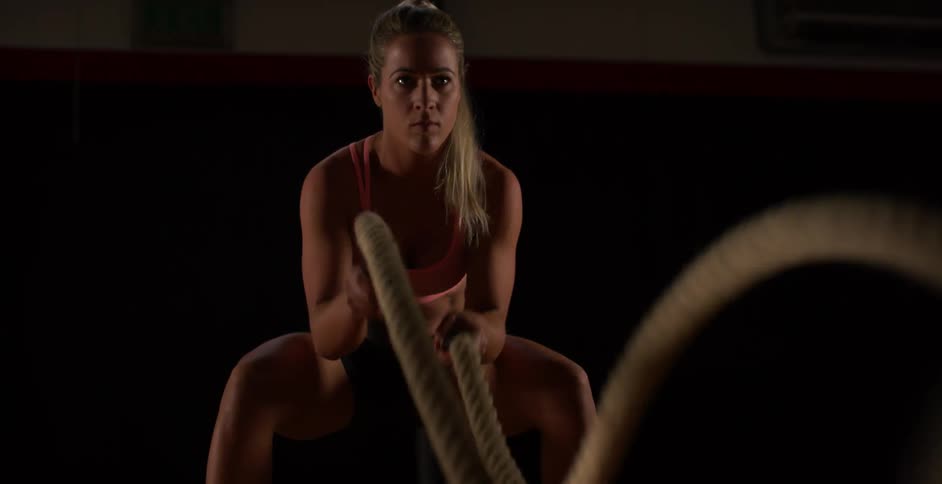 A woman exercises using two heavy ropes