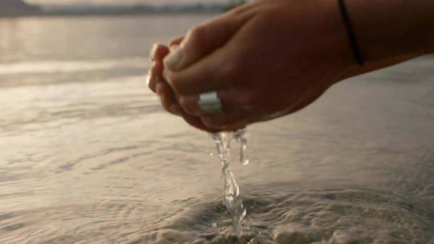 A person scoops water in their hands