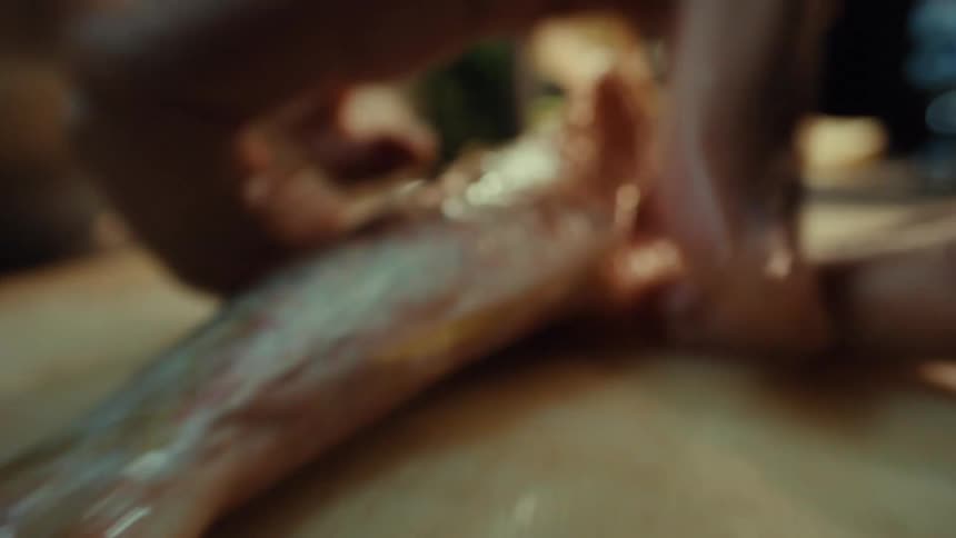 Extreme macro shot pulls out from inside a fish as a chef guts and seasons it in a kitchen