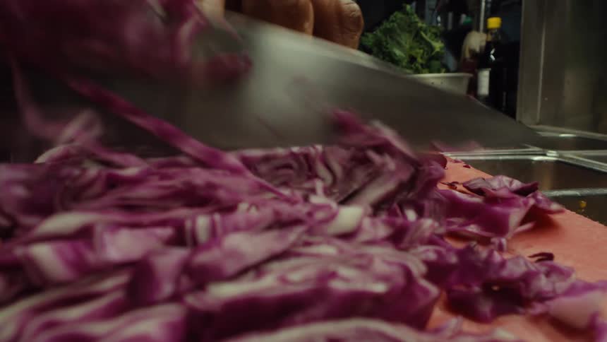 Extreme close-up macro shot of a chef swiftly chopping and shredding red cabbage on a cutting board